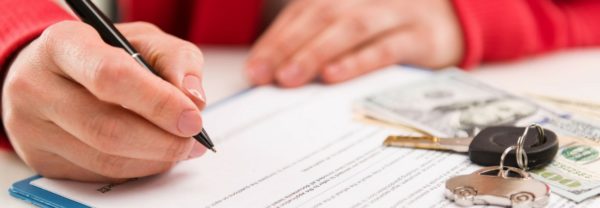 A close up of a woman signing papers with cars keys and money featured in a blog post about bad credit car loans