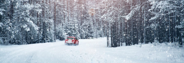 a red car driving through the snow in the winter